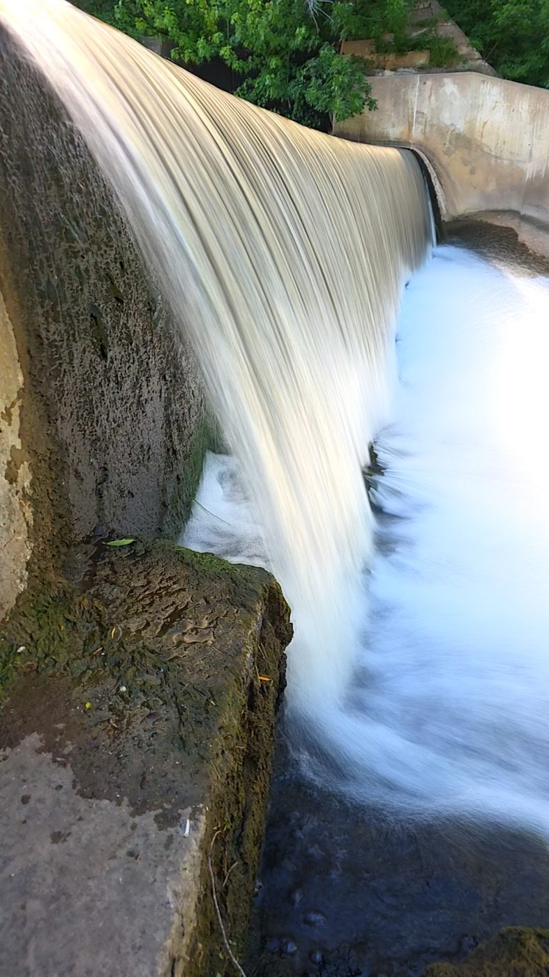 Sheet of water flowing over a dam spillway, glassy smooth